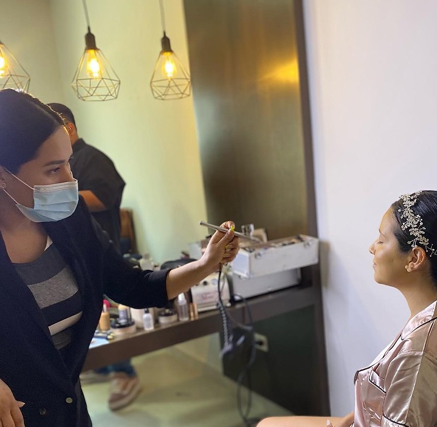 Dioseline Espinoza applying airbrush makeup to a bride